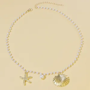 Closeup of ocean style pearl necklace with gold starfish and shell pendants, delicate design.