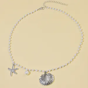 Close-up detail shot of the ocean-themed pearl necklace featuring delicate seashell and starfish charms.