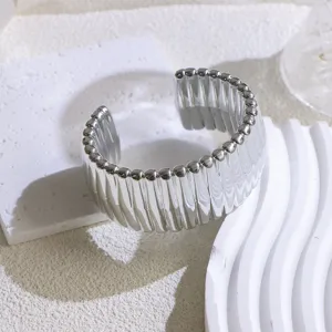 Detailed close-up of a wide silver open cuff bracelet featuring a ribbed design.