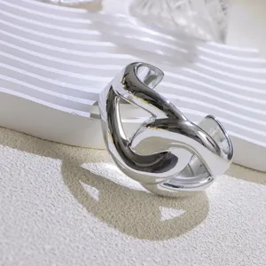 Detailed shot of a wide open cuff bracelet, chic minimalist silver metal jewelry for women.