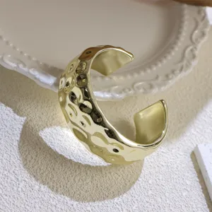Close-up of a wide gold hammered cuff bracelet, minimalist fashion open metal bracelet.
