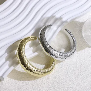 Detailed shot of gold and silver wide open cuff bracelets featuring textured organic surface.