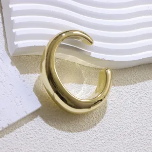 Close-up detail of wide gold open cuff bracelet, minimalist chunky metal jewelry design.