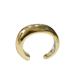 Detail shot of wide open cuff bracelet, minimalist gold tone chunky metal jewelry for modern women.