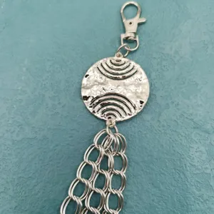 Silver metal disc pants chain detail showing punk style lobster clasp and layered chain links.