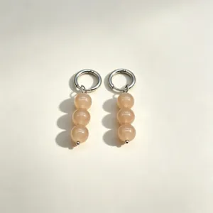 Detail view of minimalist triple-bead drop earrings with silver metal hoops and natural stones.