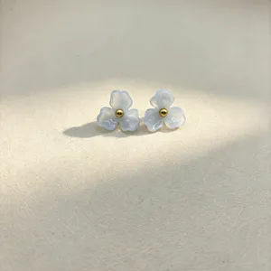 Close-up of sweet blue resin flower stud earrings with a gold bead center, elegant detail.