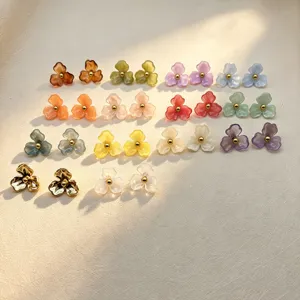 Close-up detail shot of colorful resin and metal flower stud earrings, elegant floral design.