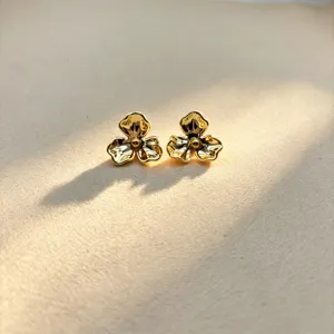 Golden flower stud earrings detail view, showcasing intricate petal design and glossy finish.