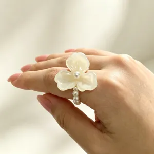 Detailopname van een chique witte driebladige bloemenparelring met elastische band.