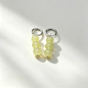 Close-up detail of light green natural stone bead dangle hoop earrings with metallic accents.
