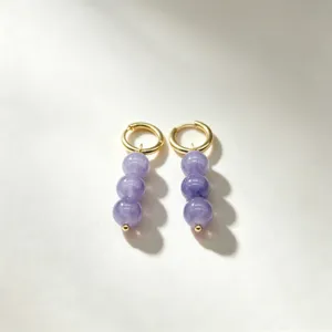 Close-up detail shot of elegant gold hoop earrings featuring vertical purple beaded drops.