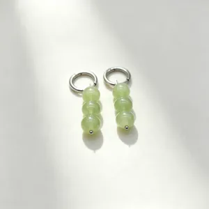 Minimalist green stone bead hoop earrings detail shot showcasing delicate metallic texture.
