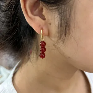 Gold-tone hoop earrings featuring a triple red bead drop design, elegant daily wear jewelry.