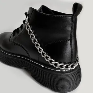 Detailed view of black platform combat boots featuring a chunky silver chain accessory.