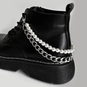 Detail shot showing the double layer pearl and metal shoe chain accessory on a black boot.