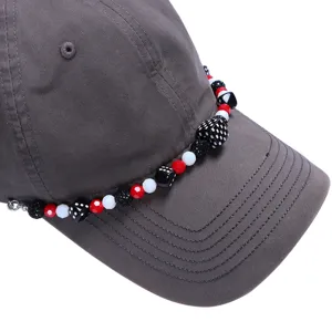 Detailopname van grijze honkbalpet met kleurrijke kralen dobbelsteen hoed ketting accessoire.