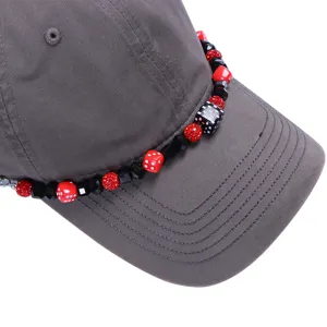 Gedetailleerde close-up van een grijze pet met een ketting van kralen, dobbelstenen en strass.