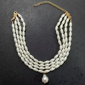Close-up detail of multi-layer imitation pearl necklace with gold extension chain and pendant.