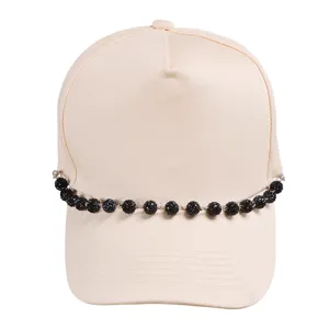 Detailed close-up of a stylish beige baseball cap featuring a sparkly black beaded chain.