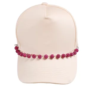 Close-up detail of rhinestone ball chain decoration on beige baseball cap, stylish accessory.