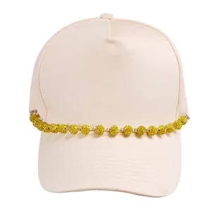 Close-up of beige baseball cap featuring sparkling yellow rhinestone ball chain detail.