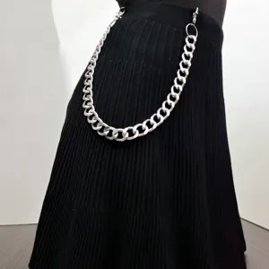 Detail shot of a chunky silver metal punk waist chain styled on black pleated skirt.