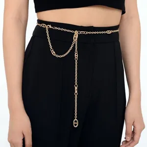 Vue rapprochée détaillée de la ceinture chaîne en métal doré portée sur un pantalon.