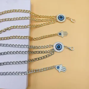 Detailed view of multi-layer metal waist chains with evil eye and hamsa hand pendants.