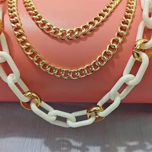 Close-up detail of chunky layered gold and white resin link chain necklace fashion jewelry.