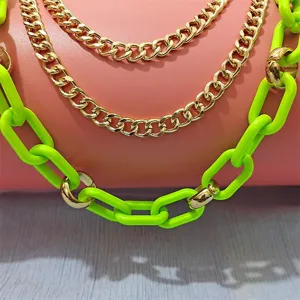 Close-up detail of punk hip-hop neon green and gold chain necklace, edgy layered design.