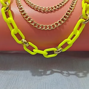 Close-up detail of punk hip-hop neon yellow resin and gold metal layered chain jewelry accessory.