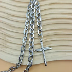 Close-up of punk style silver metal chain with nail cross pendant for streetwear fashion.
