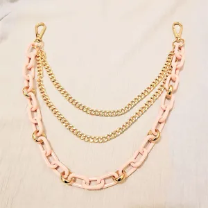 Detailed view of trendy multi-layer pink resin and gold metal chain, perfect pants and bag accessory.
