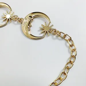 Detailed close-up of gold tone metal moon and star body chain, punk retro waist jewelry item.