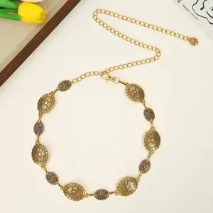 Close-up of retro metal waist chain with carved flower discs, delicate body chain design.