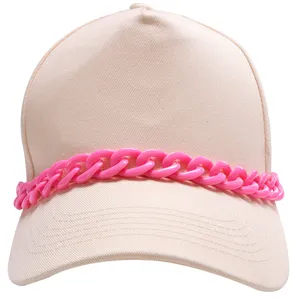 Close-up detail of a trendy beige baseball cap adorned with a vibrant pink plastic chain accessory.