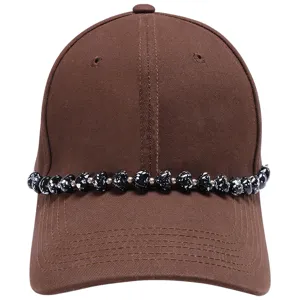 Brown baseball cap detail with black white speckled heart bead chain accessory, stylish look.