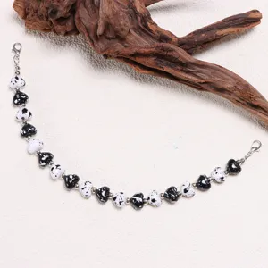 Detailed close-up of a fashionable black and white speckled heart bead hat chain accessory.