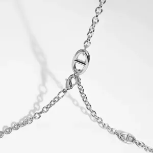 Gros plan sur la chaîne en métal argenté, maillons géométriques, accessoire minimaliste.