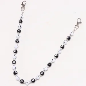 Detailaufnahme einer modischen Hosenkette mit schwarzen 8-Ball und Würfel Perlen Strass.