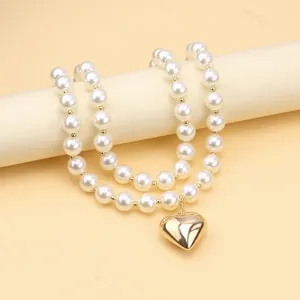 Detail view of the multi-layer faux pearl necklace featuring a shiny gold heart pendant.