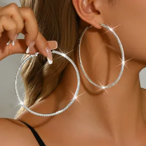 Primo piano dettagliato di grandi orecchini a cerchio in argento con strass, gioielli alla moda.