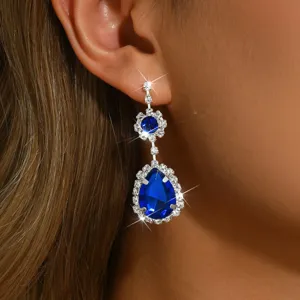 Détail en gros plan de boucles d'oreilles pendantes en cristal bleu avec strass brillants.