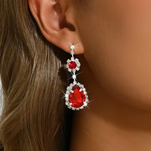 Élégantes boucles d'oreilles pendantes fleurs et cristaux rouges, détail bijou scintillant.