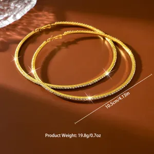 Primo piano dettagliato di grandi orecchini a cerchio dorati con strass scintillanti.