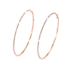 Primo piano dettagliato di grandi orecchini a cerchio in oro rosa con strass, gioiello luminoso.