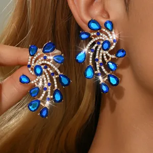 Primo piano dettagliato di orecchini pendenti in cristallo blu con strass luminosi.