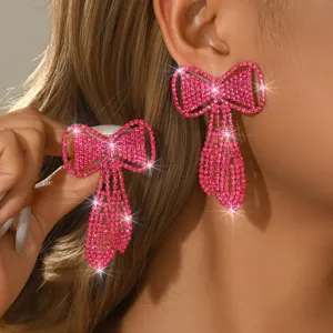 Nahaufnahme von glitzernden rosa Strass Schleife Quaste Ohrringen, luxuriöser Modeschmuck.