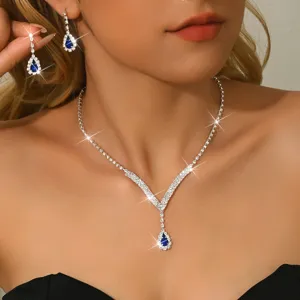 Elegante set di gioielli con collana e orecchini in strass a goccia blu scuro.